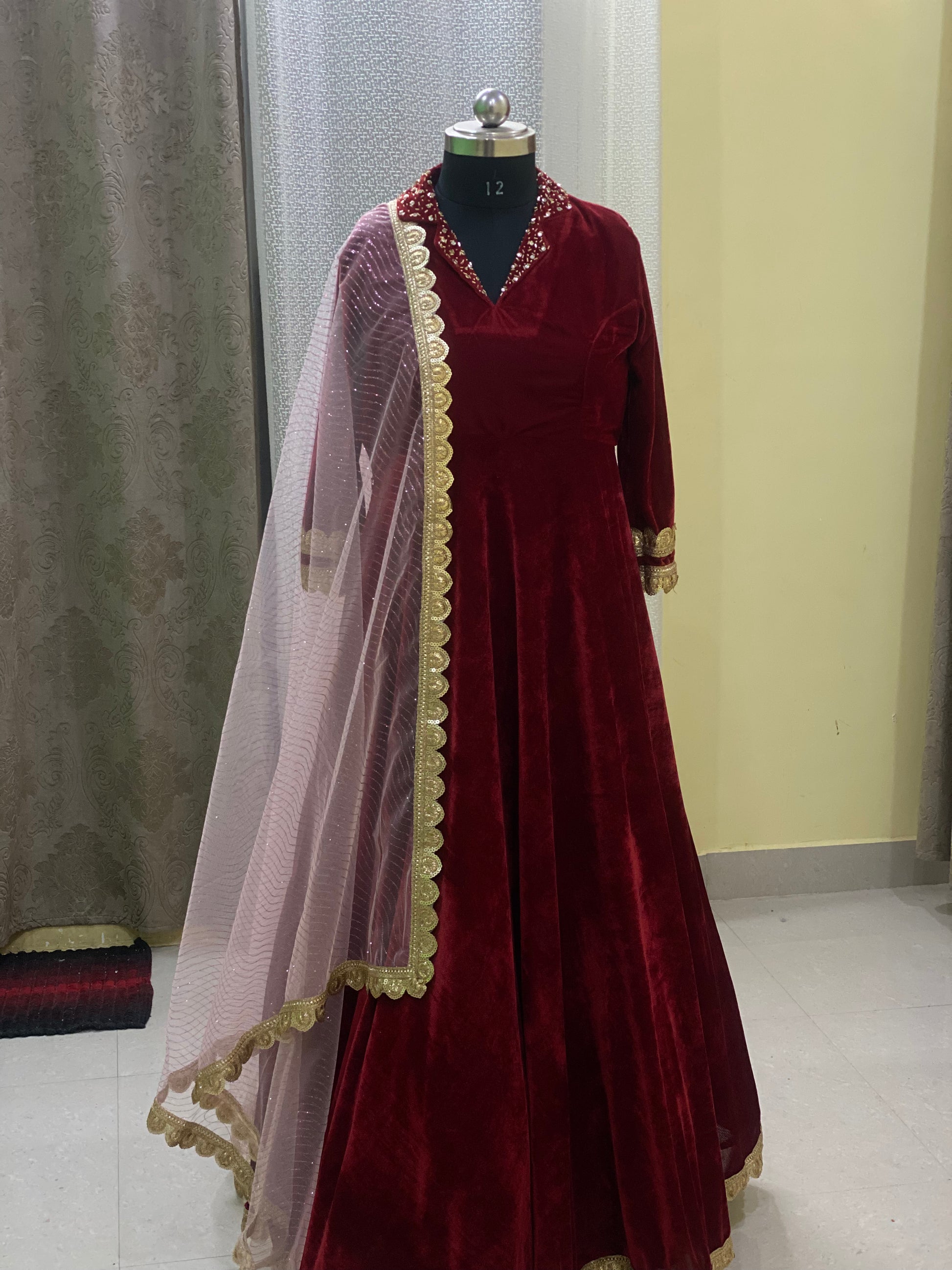 Maroon velvet dress with a sheer pink dupatta on a mannequin
